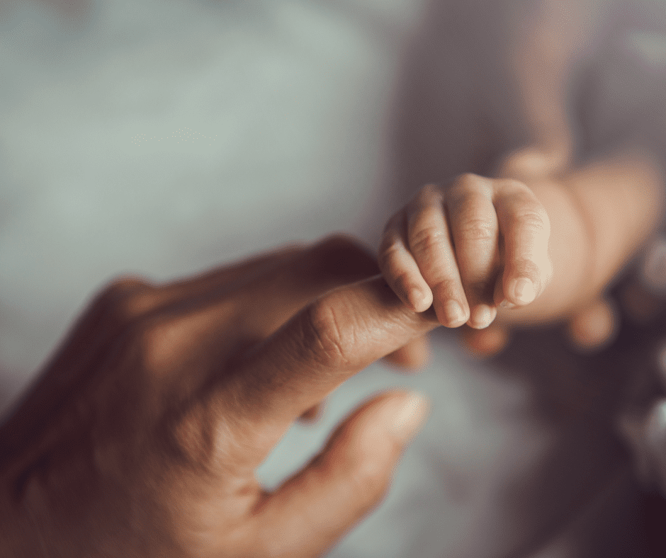 Close-up of a baby’s hand grasping an adult’s finger, symbolizing parental connection and early childhood bonding.
