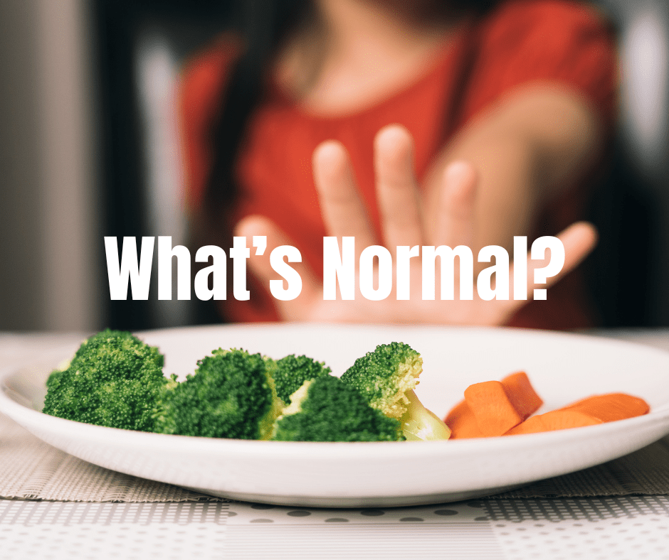 Child in red shirt refusing plate of broccoli and carrots with hand held up in rejection.